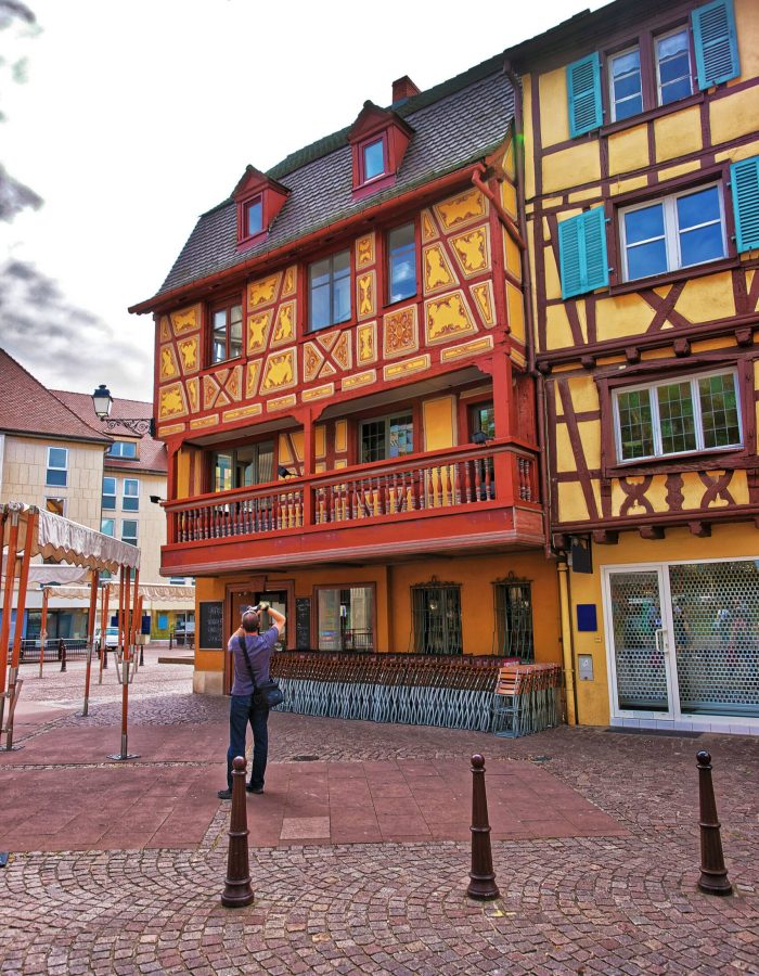 colorful-timber-framing-houses-on-rue-des-tetes-street-in-the-old-city-center-of-colmar-haut-rhin-in-alsace-of-france-people-on-the-background-scaled.jpg