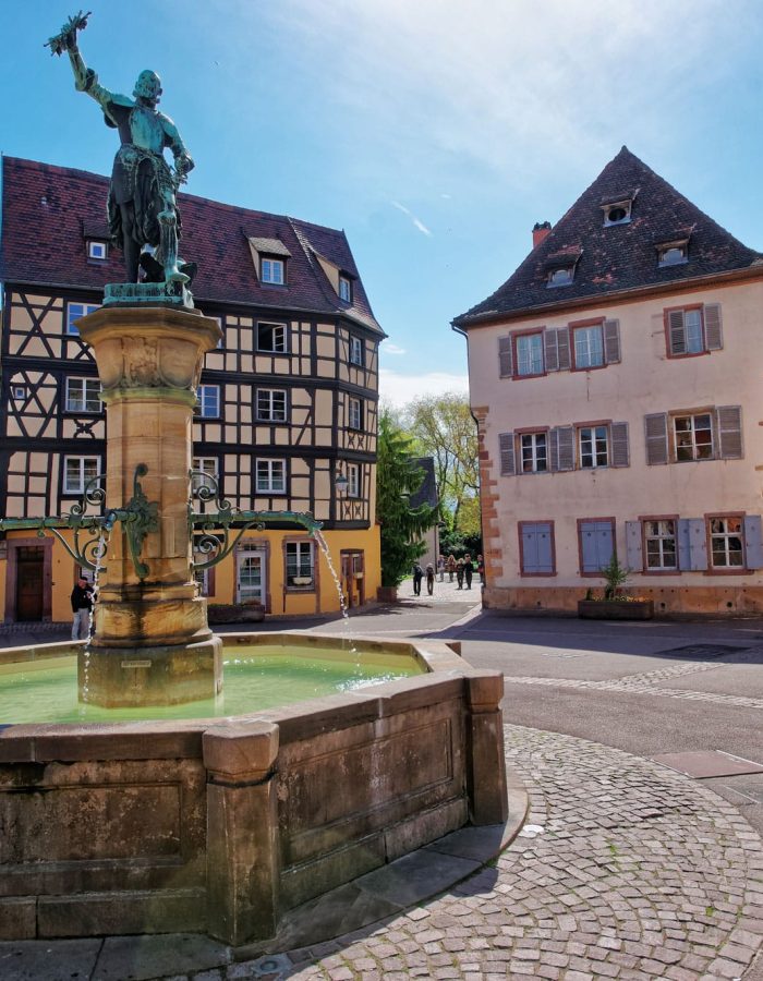 old-city-center-and-schwendi-fountain-at-place-de-ancienne-douane-square-in-colmar-haut-rhin-in-alsace-in-france-people-on-the-background.jpg